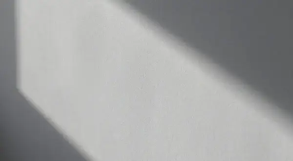 Światło podkreśla nierówności na elewacji, tworząc cień o geometrycznym kształcie.
