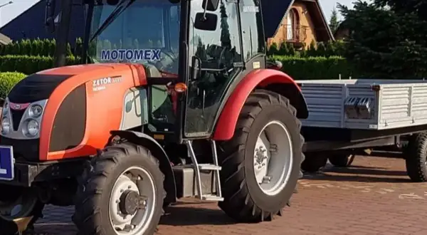 Czerwony Zetor z przyczepą, gotowy do pracy. Posiadanie prawa jazdy na traktor otwiera drogę do takich maszyn.
