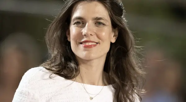 Charlotte Casiraghi sonríe con un collar delicado y un suéter blanco.