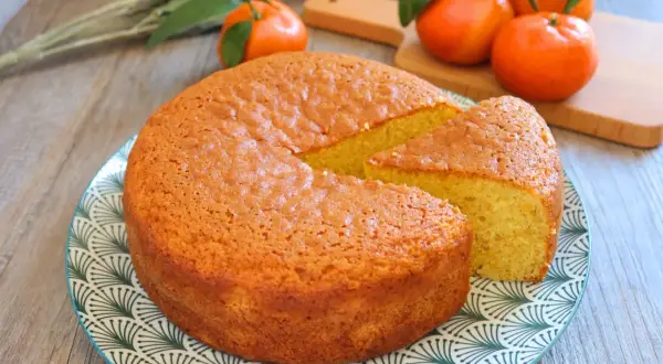 Bizcocho de mandarina esponjoso y dorado, con una porción cortada, listo para disfrutar.