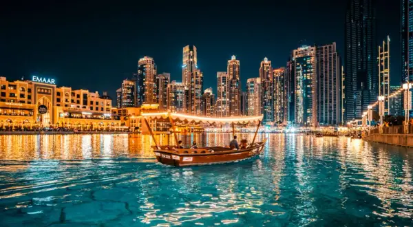 En båt glider fram på vattnet i Dubai i december, med upplysta skyskrapor som bakgrund.