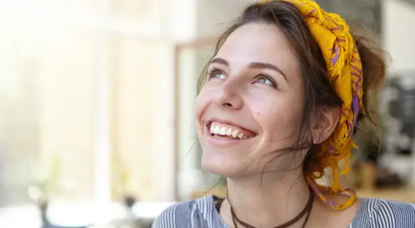 Uśmiechnięta dziewczyna z żółtą chustą na głowie. Jej radość i naturalność to coś, co mężczyźni lubią w kobietach.