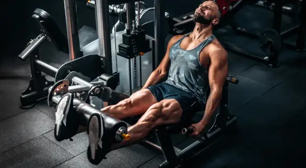 Mann trainiert Beine an einer Maschine, die Kraft durch Push- und Pull-Bewegungen aufbaut.