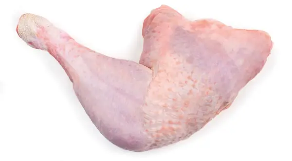 Una zampa di tacchino cruda, con la pelle rosata e squamosa alla fine, pronta per essere cucinata.
