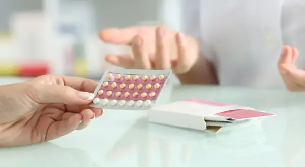 Dłoń trzyma blister tabletek antykoncepcyjnych. Czy przy antykoncepcji jest owulacja? Farmaceutka wyjaśnia.