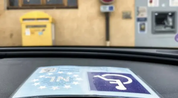 Karta parkingowa dla niepełnosprawnych uprawnienia, symbol wózka inwalidzkiego na niebieskim tle.