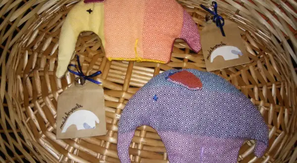 Due elefantini di stoffa colorati, perfetti per lavoretti con la stoffa per bambini. Uno arancione e giallo, l'altro viola e blu, con etichette "made by carla".