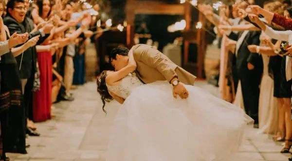 Coppia si bacia tra scintille di bengala, circondata da invitati festanti. Un momento magico, come i migliori giochi matrimonio.