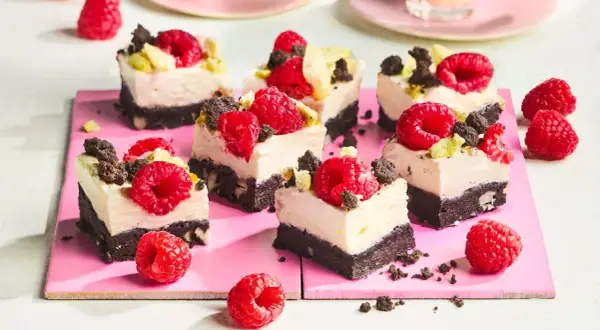 Kleine, cremige Kuchenstücke mit Himbeeren und Schokostückchen, perfekt für den Sommer.