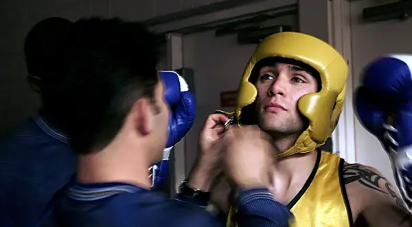 A boxer in a yellow headguard and vest gets ready for the fight, wondering how many rounds in boxing he'll endure.