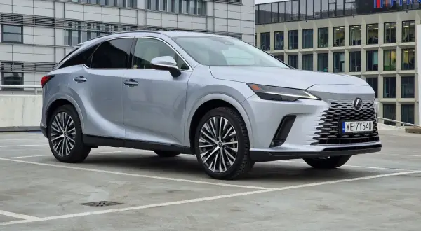 Srebrny Lexus RX350h zaparkowany przed nowoczesnym budynkiem biurowym.