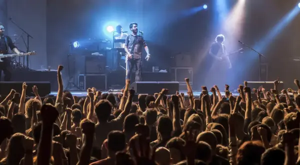 Una banda en vivo toca para una multitud eufórica. Los **fiz horarios** de la música llenan el aire mientras los fans levantan los puños.