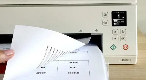 Dłoń wsuwa papier do drukarki, na ekranie widoczny numer 1 i opcja "Kopia cz.-biała".