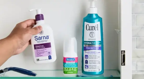 Dłoń sięga po balsam Sarna, by złagodzić swędzące plecy. Obok spray Benadryl i balsam Curél.