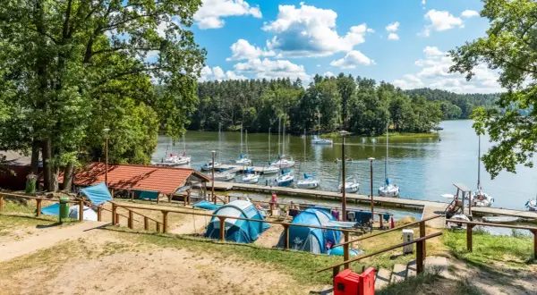 Namioty rozbite nad jeziorem, gdzie cumują żaglówki. Idealne miejsce na wypoczynek, prawdziwy pole namiotowe Mazury.