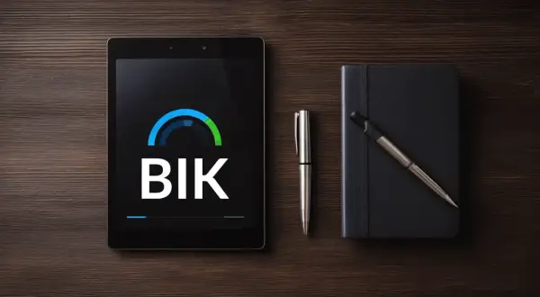 Tablet z logo BIK, długopis i czarny notatnik na drewnianym tle.