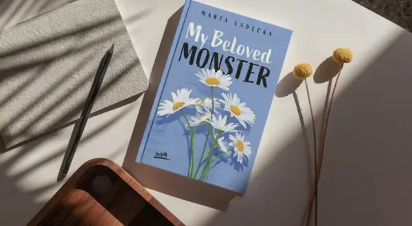 Okładka książki "My Beloved MONSTER" Marty Łabeckiej, z motywem stokrotek. To piękna miłość książka dla dzieci, która zachwyci najmłodszych.