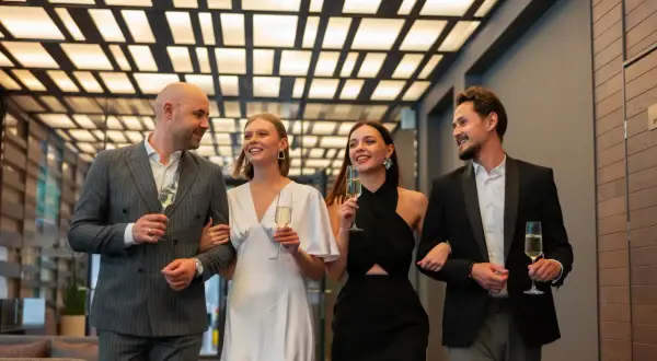 Elegancka para i ich znajomi, świętujący przy szampanie. Wszyscy przestrzegają nienagannego dress code'u na wieczorne wyjście.