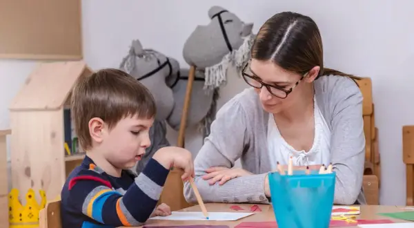 Nauczycielka wspiera chłopca z zespołem Aspergera w rysowaniu. Skupienie na zadaniu, a nie na tym, jak karać dziecko z zespołem Aspergera.