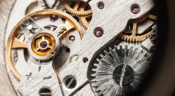 Detalle de un mecanismo de reloj, mostrando engranajes y el volante, que es un oscilador, en su interior.