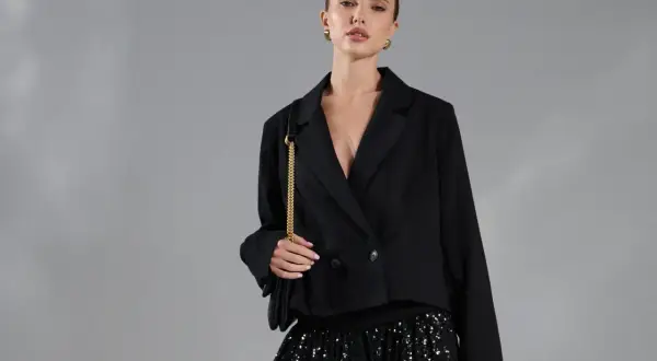 Modelka w czarnej marynarce i błyszczącej spódnicy z cekinami.