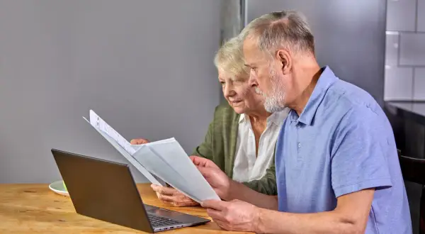 Para seniorów analizuje dokumenty przy laptopie. To przykład ulgi dla seniora w PIT-37.