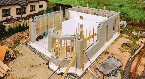 Budowa domu ze styropianu w postępie. Widać fundamenty, ściany z bloczków i elementy szalunku.