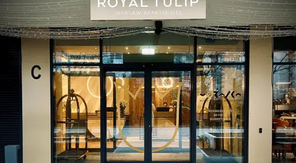 Eleganckie wejście do Royal Tulip Warsaw Apartments z widocznym logo i recepcją.