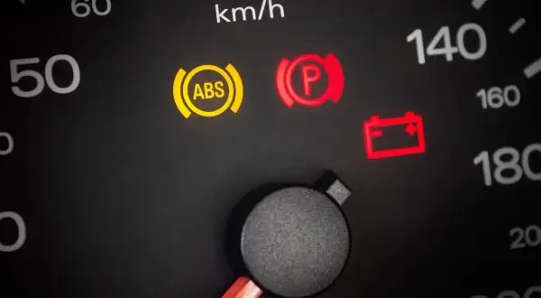 Tableau de bord avec voyant ABS allumé, signalant un problème à tester. Le frein de parking est aussi activé.