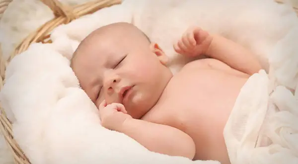 Śpiące dziecko w koszyku, otulone miękkimi kocykami. Marzy o podwójnym becikowym.