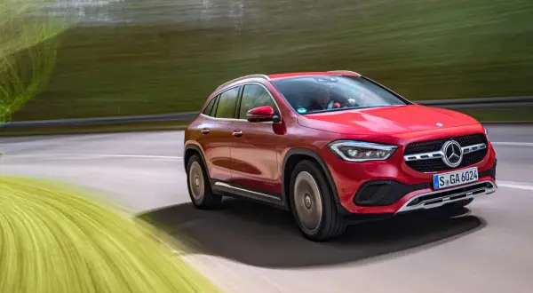 Röd Mercedes GLA på en testkörning längs en grönskande väg.