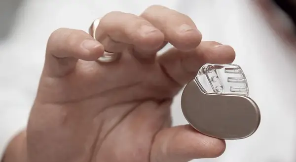 Dłoń trzymająca niewielki pacemaker. Dzięki niemu można wrócić do aktywności, nawet do biegania.