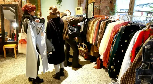 W sklepie z odzieżą vintage, gdzie króluje styl retro, kobiety przeglądają ubrania. To właśnie co oznacza słowo vintage – moda z minionych dekad.
