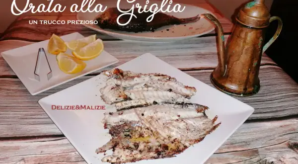 Orata alla griglia succulenta, servita con spicchi di limone e un'antica oliera in rame. Un vero tesoro culinario.