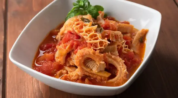 Trippa in umido con pomodoro e basilico, un piatto saporito che contiene ingredienti semplici ma gustosi.