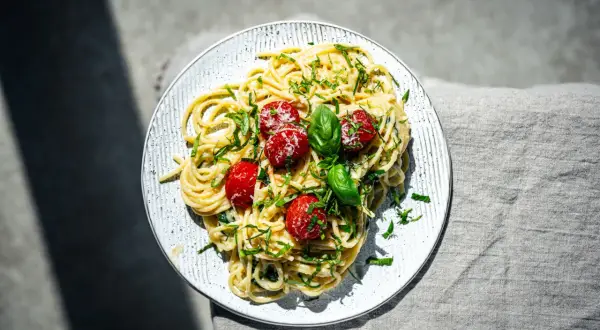 Spaghetti mit cremigem Pesto Trapanese, garniert mit Kirschtomaten und Basilikum.