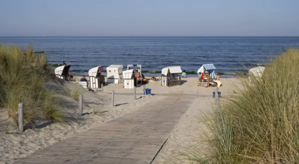 Strandkörbe am Ostseestrand, ein Holzweg führt zur See. Ein Hauch von Berlin-Urlaub an der Küste.