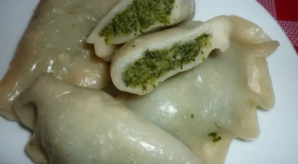 Pyszne pierogi ze szpinakiem i mozzarellą, jeden przekrojony, ukazujący zielone nadzienie.