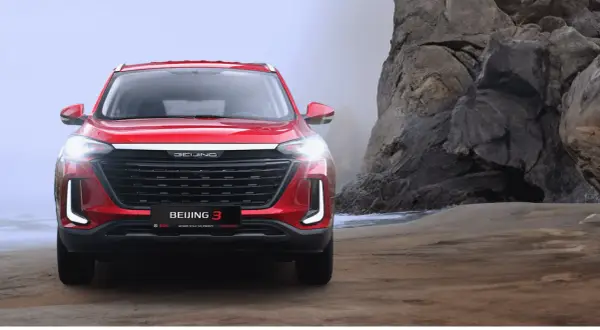 Czerwony BAIC Beijing 3 na tle skalistej plaży.