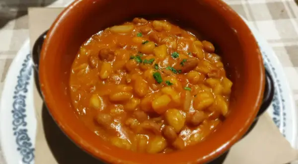 Fagioli in umido, un classico per scoprire cosa mangiare a Piacenza. Serviti in una ciotola di terracotta, sono un piatto saporito e confortante.