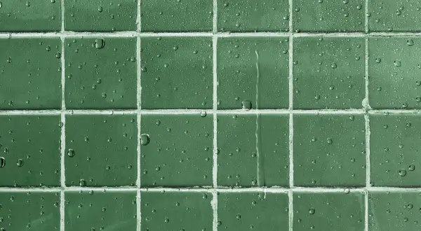 Gouttes d'eau sur un carrelage vert, montrant l'efficacité d'un traitement pour imperméabiliser un carrelage poreux.