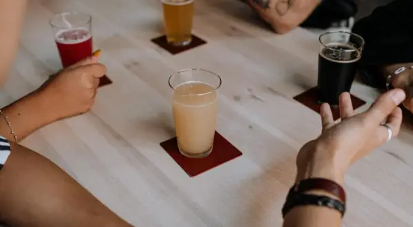 Degustacja piw belgijskich. Na stole cztery szklanki z różnymi piwami: czerwonym, jasnym, miodowym i ciemnym.