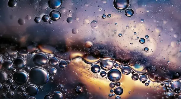 Close-up of oil and water bubbles with iridescent colors and reflections.