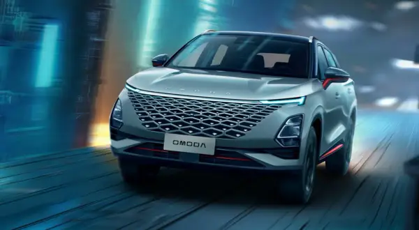 Nowoczesny SUV OMODA pędzi nocą przez futurystyczne miasto. Omoda co to za marka? To styl i innowacja.