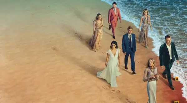En grupp människor i eleganta kläder går längs en strand. Kanske är de det perfekta paret, eller så döljer de mörka hemligheter.