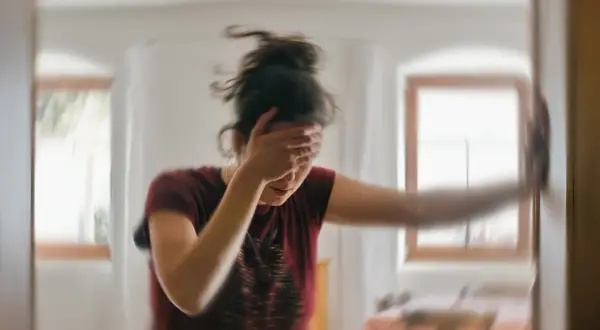 Kobieta z ręką na czole, rozmazana, jakby po ataku. Czy można pić alkohol przy padaczce?