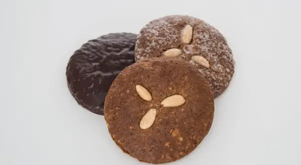 Drei runde Elisenlebkuchen, einer schokoladenüberzogen, die anderen mit Mandeln verziert. Beste Elisenlebkuchen für den Genuss.