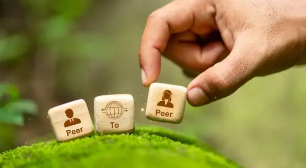 Dłoń układa kostki symbolizujące p2p: "Peer To Peer".