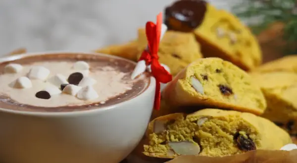 En kopp varm choklad med marshmallows och saffransbiscotti med mandel, perfekt för en mysig stund.