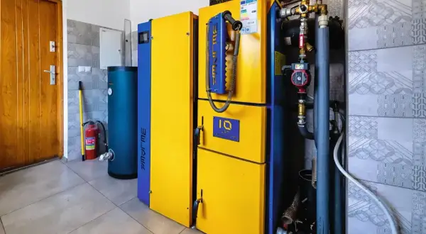 Nowoczesny piec gazowy 24kW, idealny do ogrzania domu o powierzchni do 240 m². Obok zasobnik wody i gaśnica.